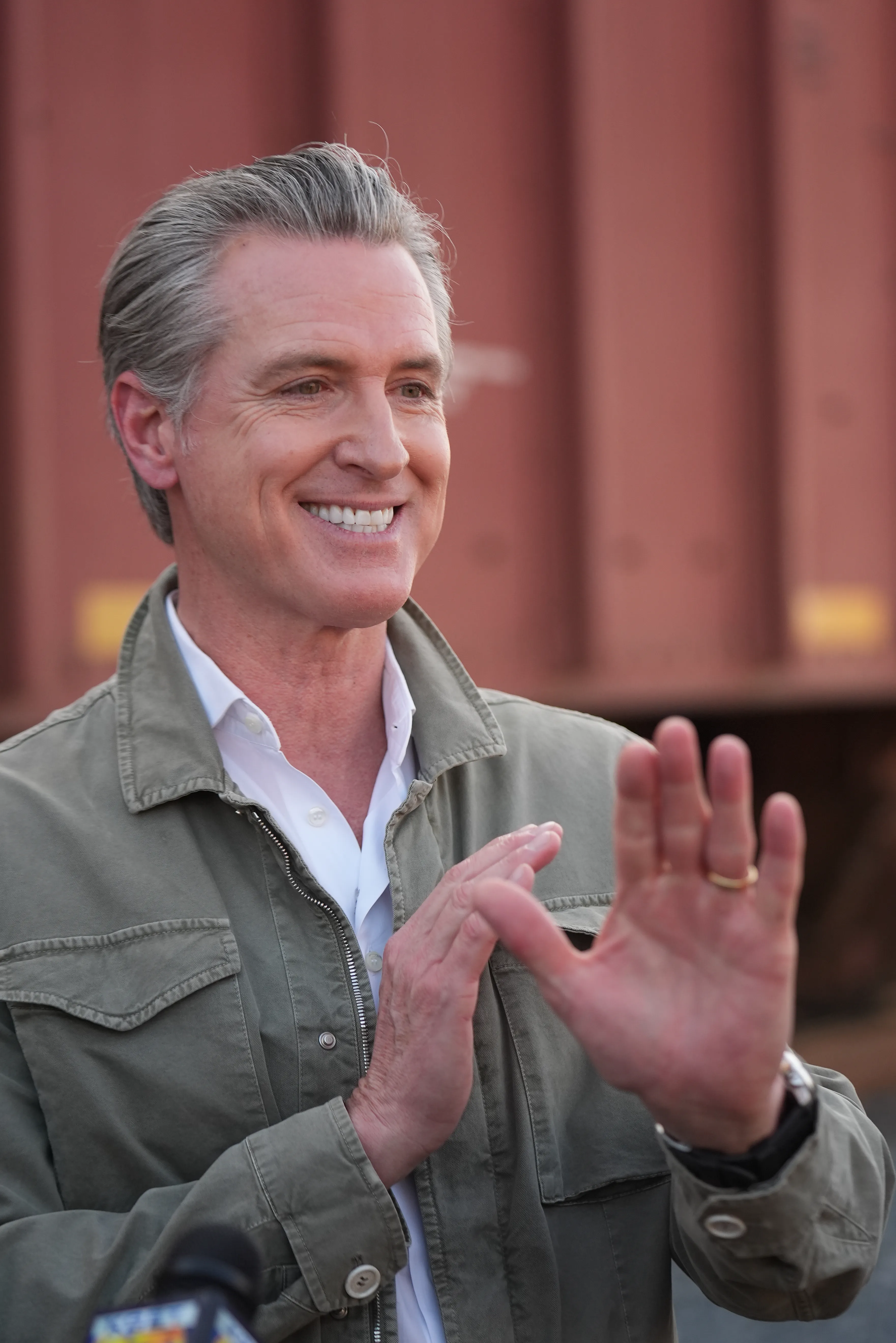 Gavin Newsom smiling and holding up a hand.