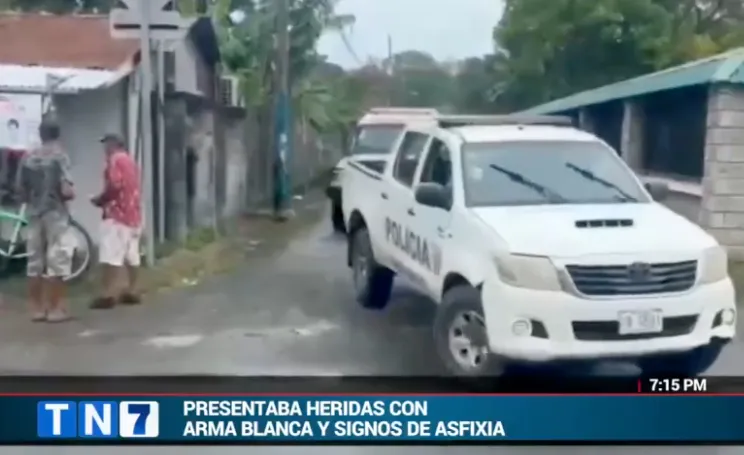 Police vehicle parked on a street with two men standing nearby.