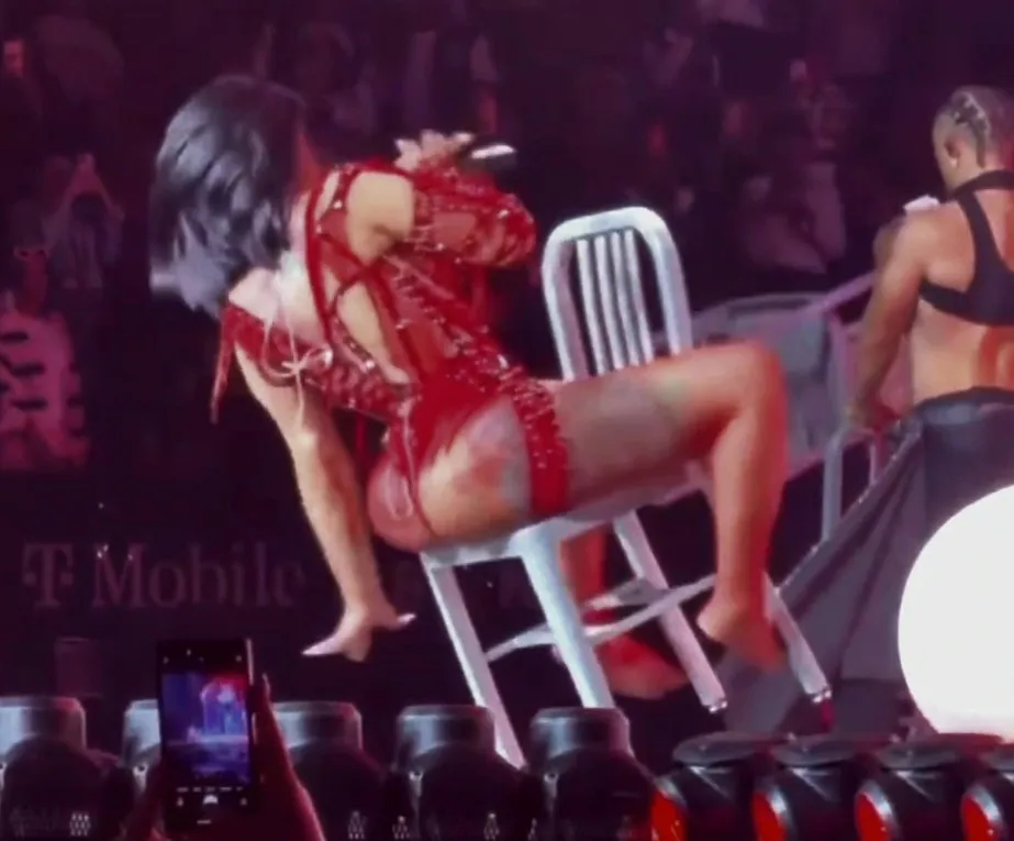 Cardi B falling backward out of a chair during a concert performance.