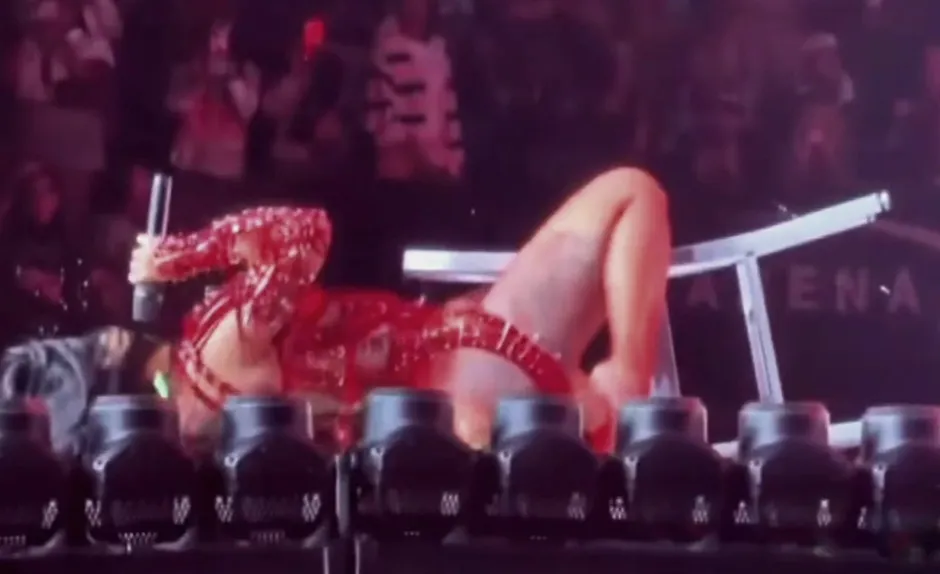 Cardi B falling backward out of a chair during a concert performance.