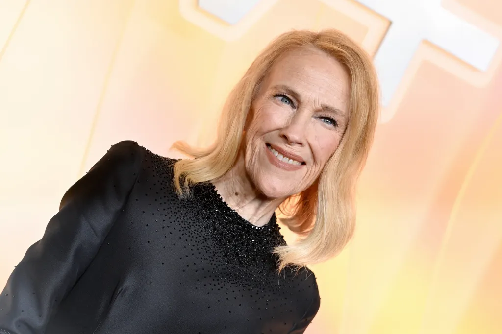 Catherine O'Hara smiles, wearing a black top with beaded embellishments.