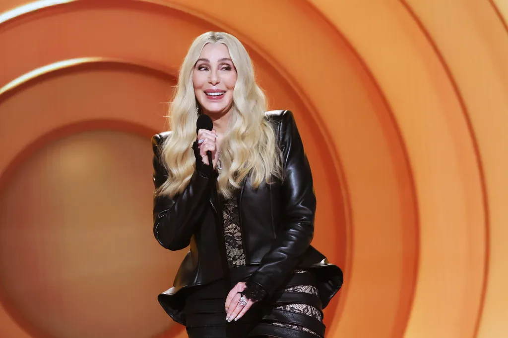 Cher speaking into a microphone onstage at the 68th GRAMMY Awards.