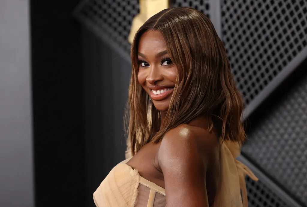 Coco Jones smiles while posing at the Grammy Awards.
