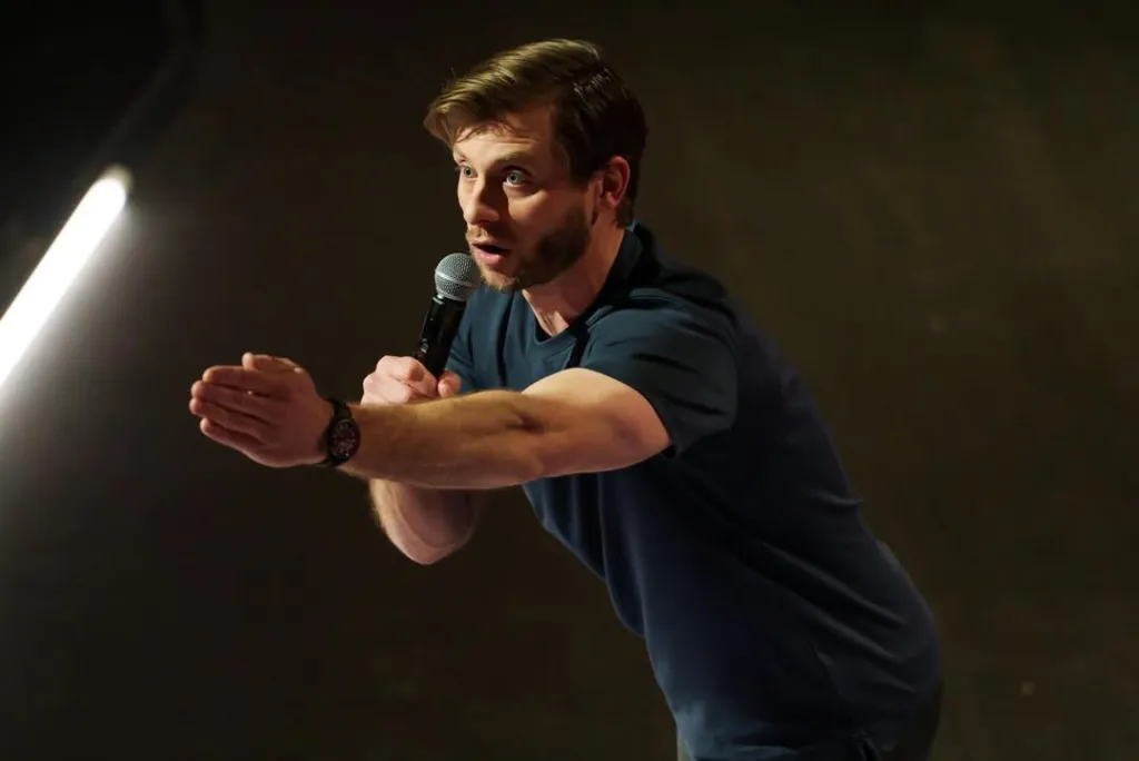 Charlie Behrens on stage speaking into a microphone.