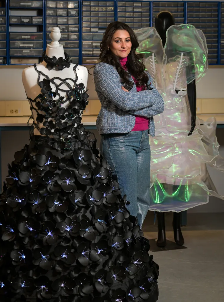 Maia Hirsch stands between two robotic dresses she designed.