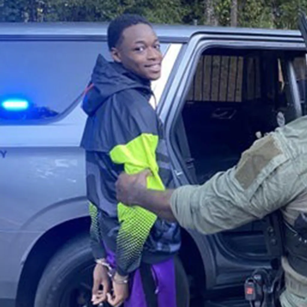 displayed a menacing grin while he was hauled away in handcuffs to a Spalding County Sheriff's squad car, chilling arrest photos show.