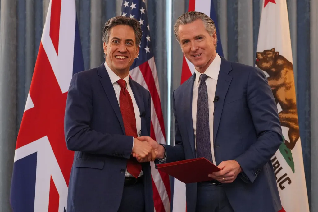 Ed Miliband and Gavin Newsom shaking hands after signing a clean energy agreement.