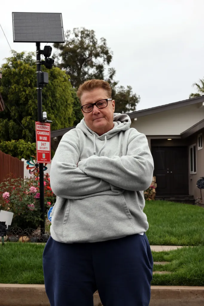 Debbie Stopeck stands in front of her Valley Glen home, which is equipped with security cameras and a warning sign.