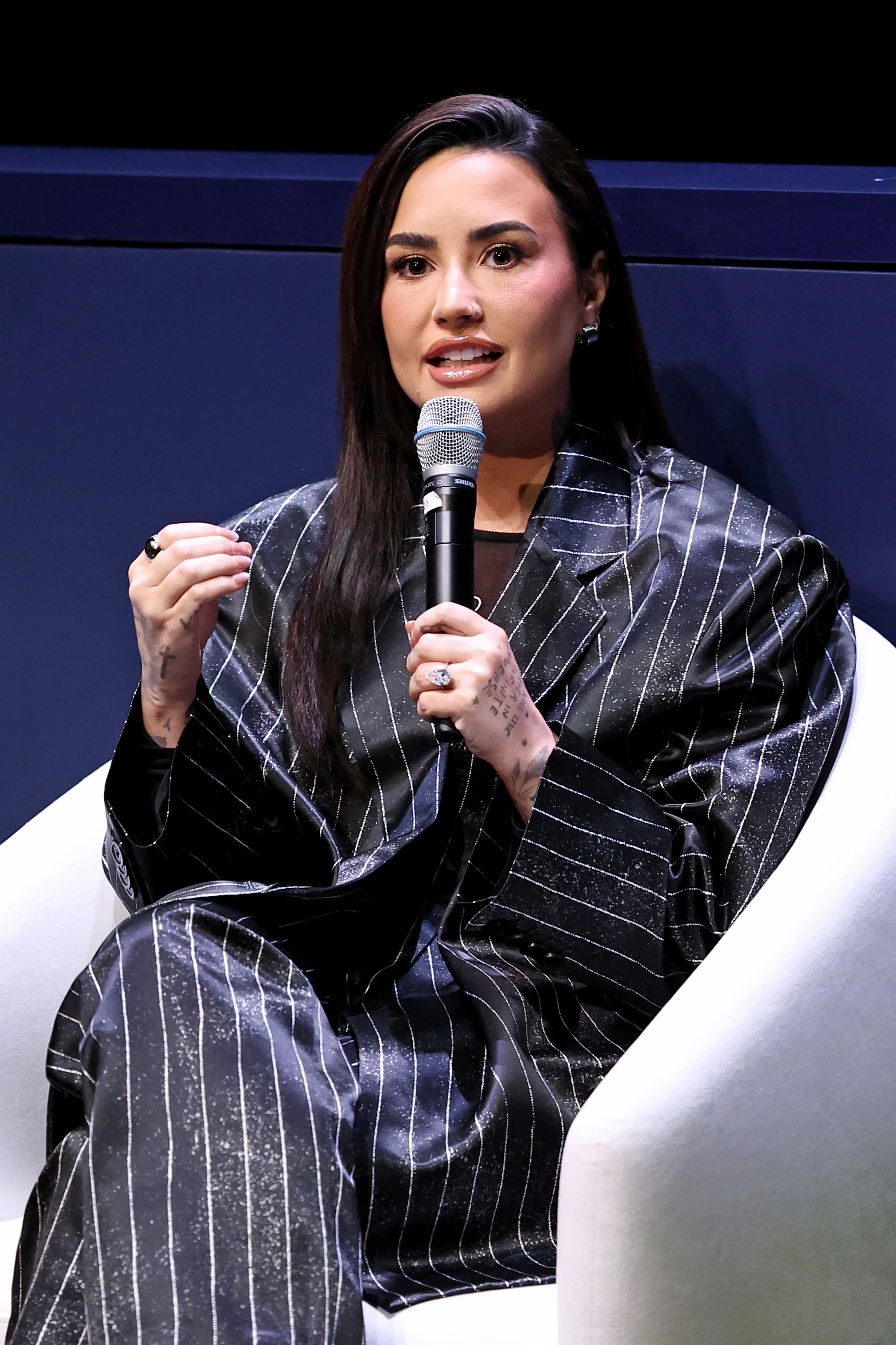 Demi Lovato speaking onstage at the Project Healthy Minds World Mental Health Day Festival.