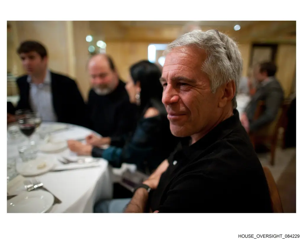 Jeffrey Epstein seated at a table with other people in a restaurant.