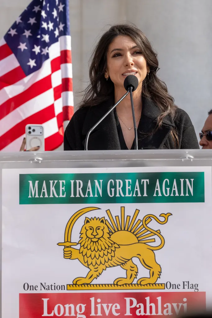 A woman speaking at a podium with a sign that reads 