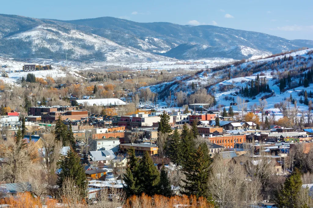 Downtown Steamboat Springs, Colorado, on a sunny winter day, with snow-covered mountains in the background.