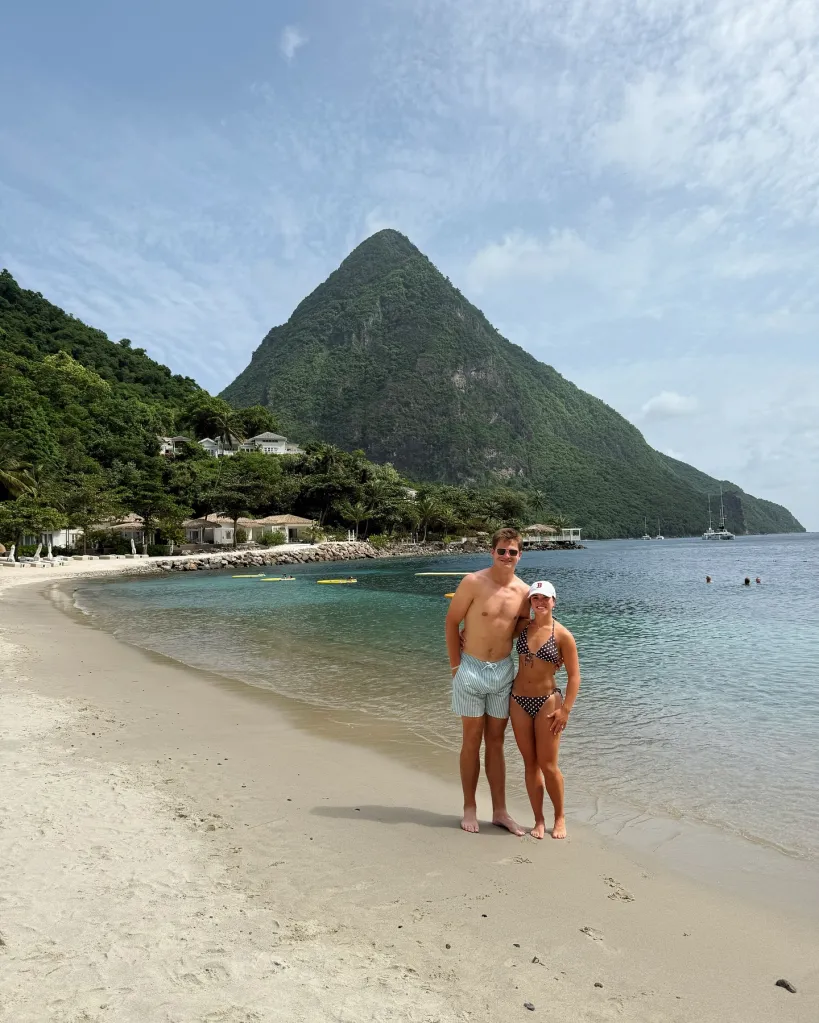 Drake Maye and Ann Michael Maye on a beach with a lush green mountain in the background.