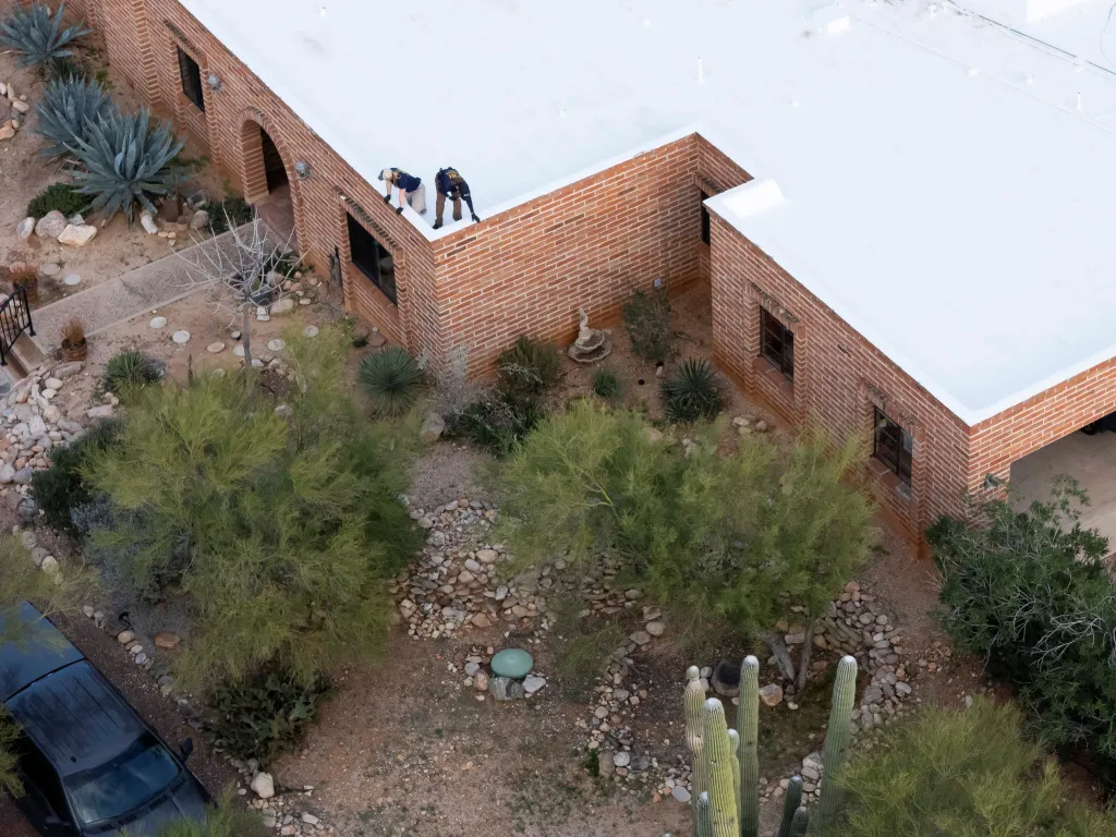 Law enforcement agents walk on the roof of Guthrie's home during an investigation.