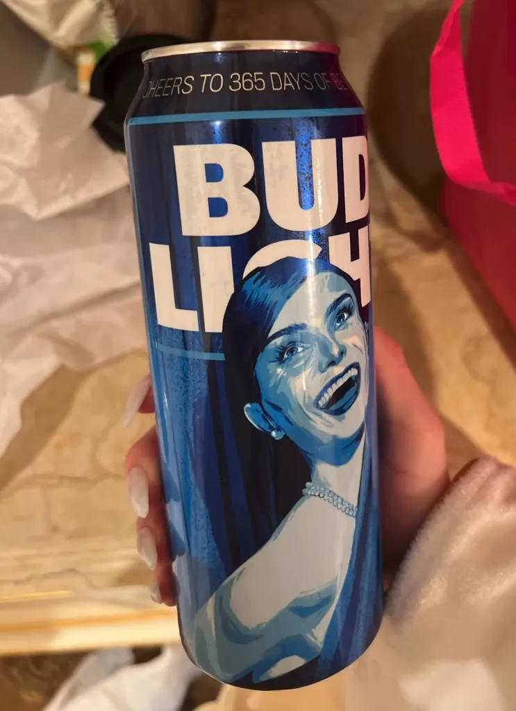 A hand holds a special edition Bud Light can featuring an illustration of Dylan Mulvaney.