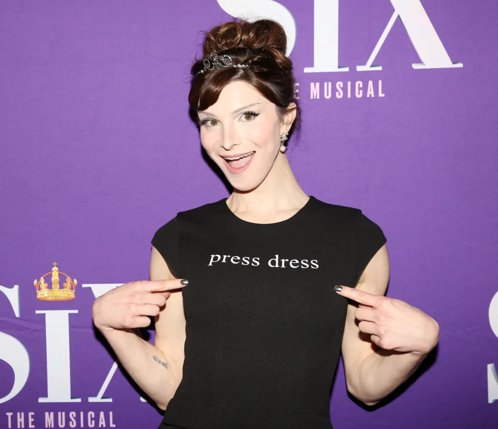 Dylan Mulvaney poses in a black dress that says 