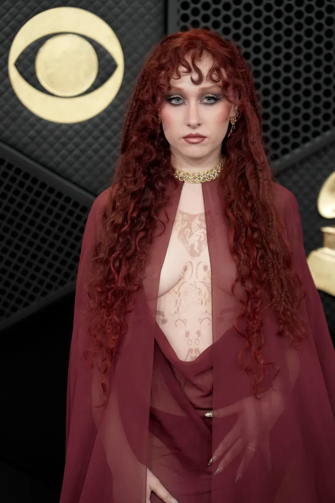 Chappell Roan at the 68th Grammy Awards in a sheer red cloak and an intricate body paint design.