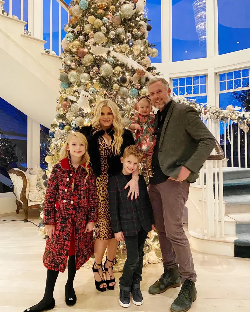 Eric Johnson, Jessica Simpson, and their three children stand in front of a Christmas tree.