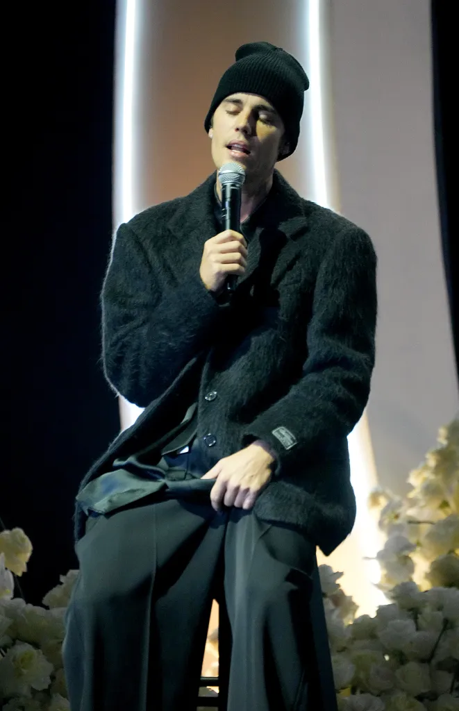 Justin Bieber performing onstage, holding a microphone.
