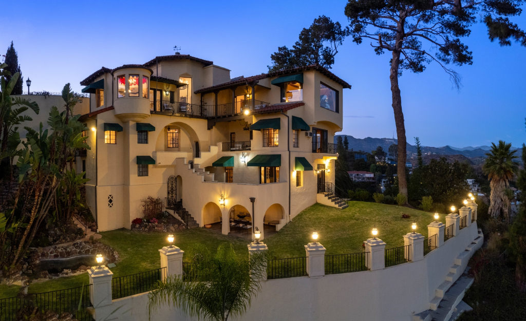 Frank Sinatra's former Los Angeles mansion, a large luxury home with terraced landscaping and views of the Hollywood sign, at dusk.