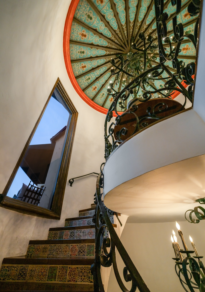 Frank Sinatra's former Los Angeles home features a spiral staircase with intricate tiling and a large ornamental chandelier.
