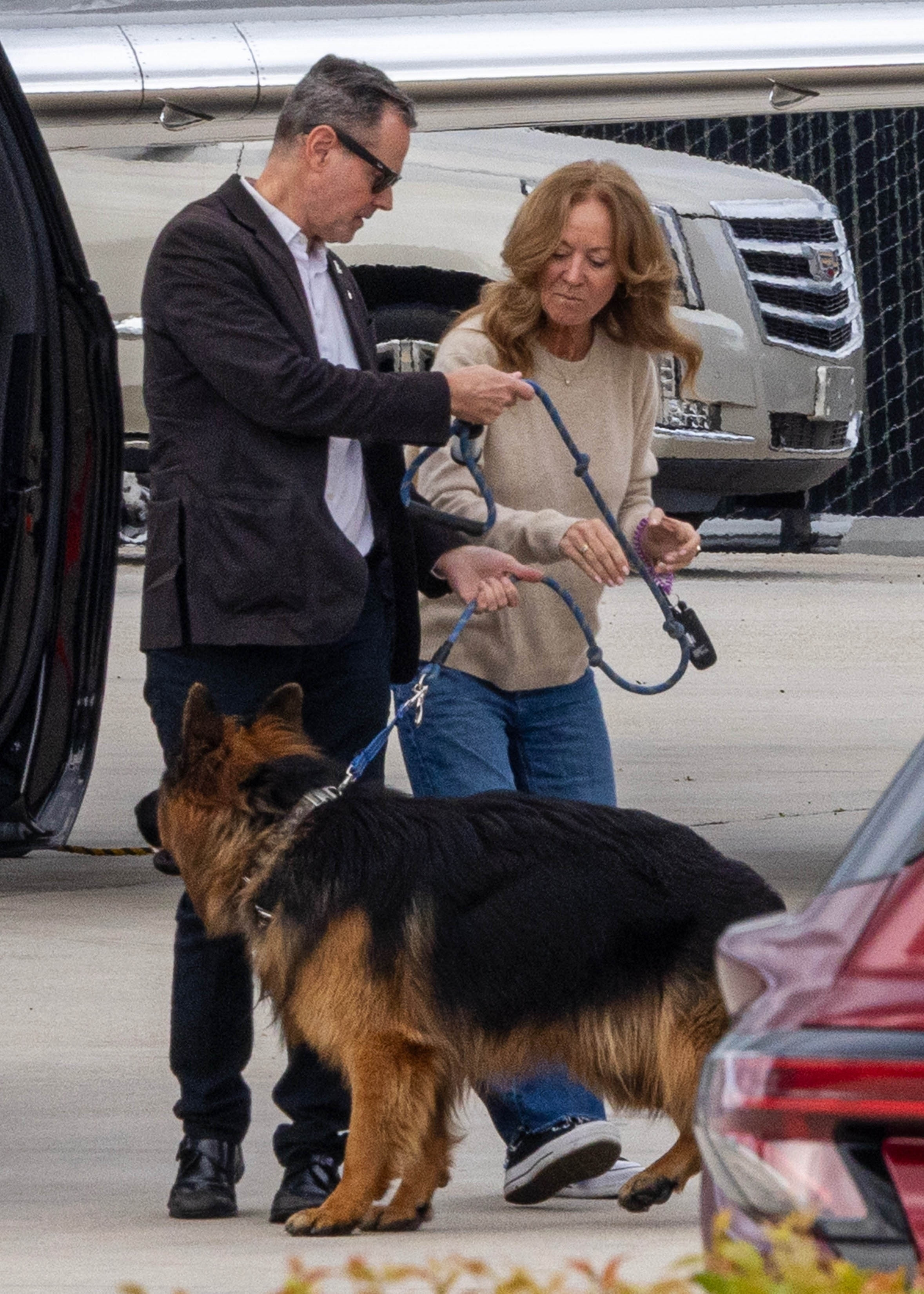 Lisa Sweeney holding a German Shepherd's leash with a man next to her.