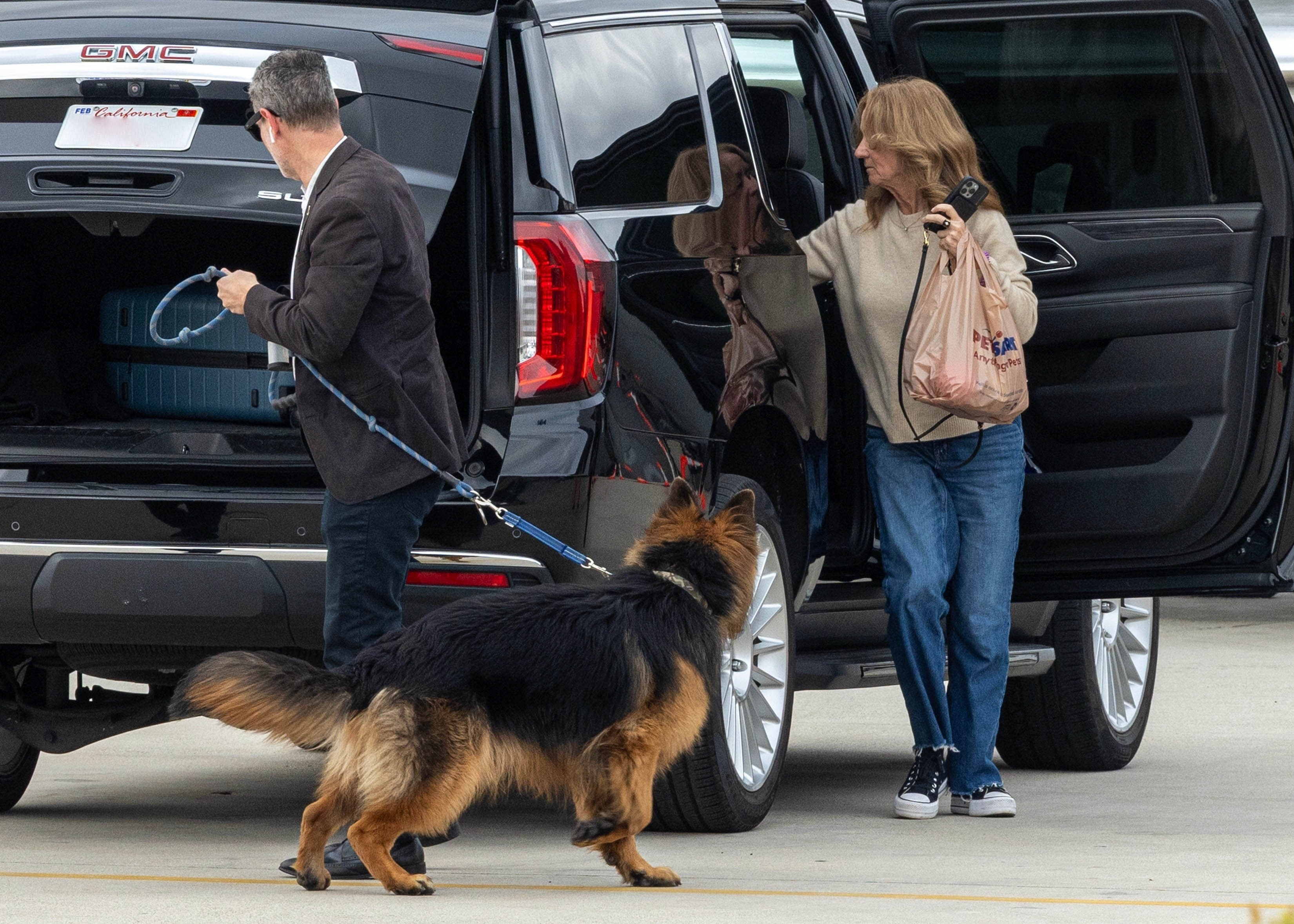 Lisa Sweeney and her dog next to a black SUV.