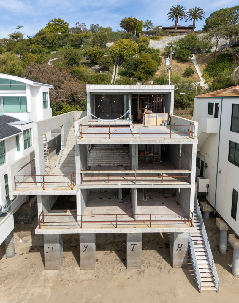 Aerial view of Kanye West's multi-million dollar Malibu beach house, which is an unfinished shell of concrete construction on stilts over the sand, flanked by two other finished beach houses.