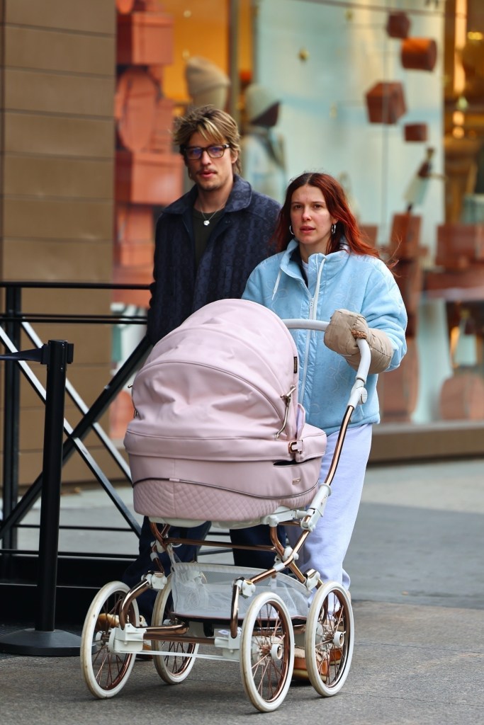 Millie Bobby Brown pushes a pink stroller while Jake Bongiovi walks beside her.