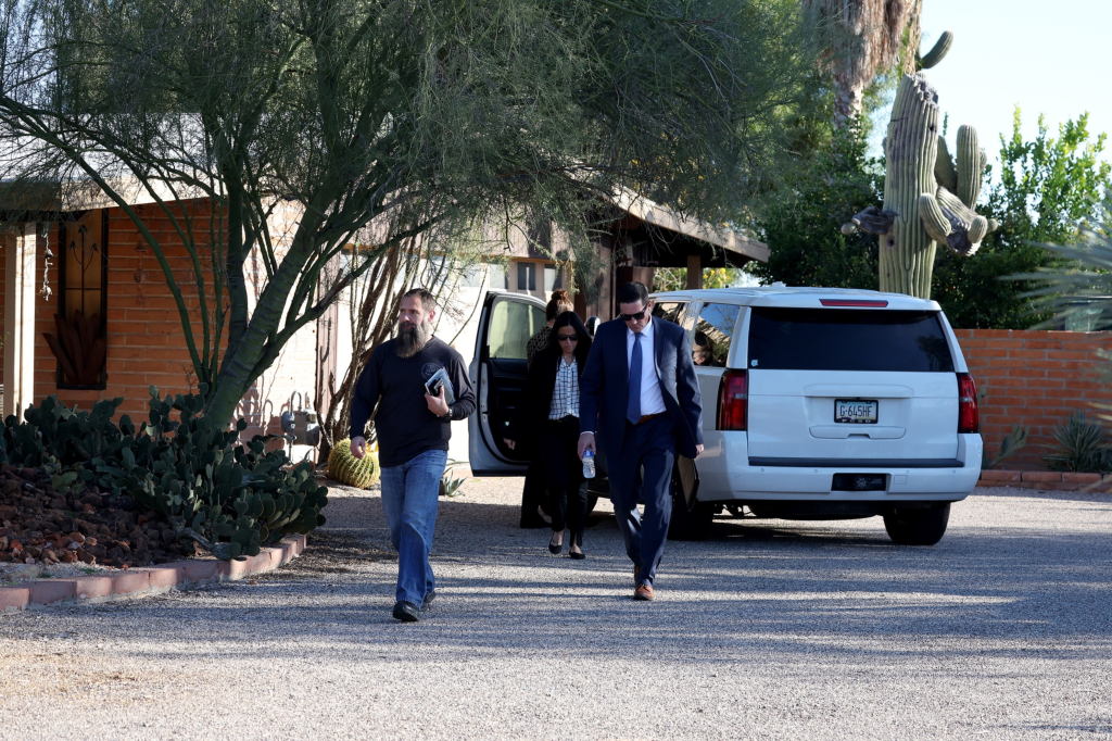 Law enforcement officers walking away from Savannah Guthrie's sister's Tucson home.