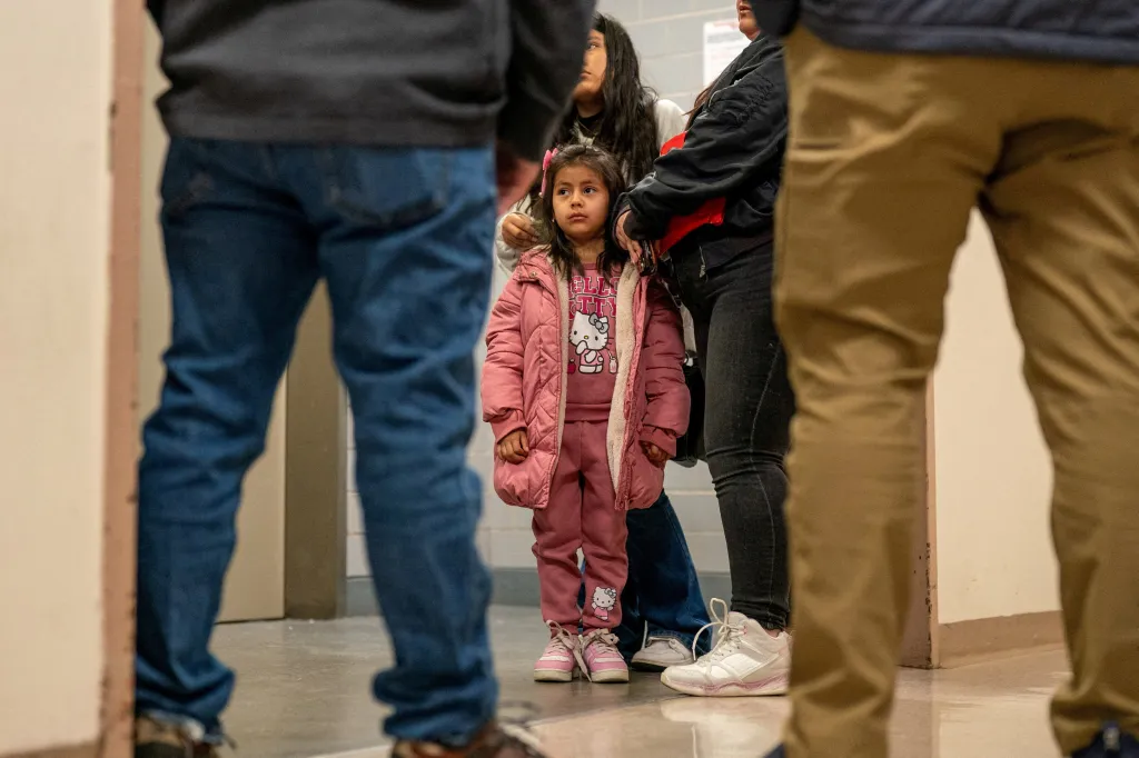 A young girl in a pink coat and Hello Kitty shirt with her family waiting at the U.S. Immigration Court in Manhattan.