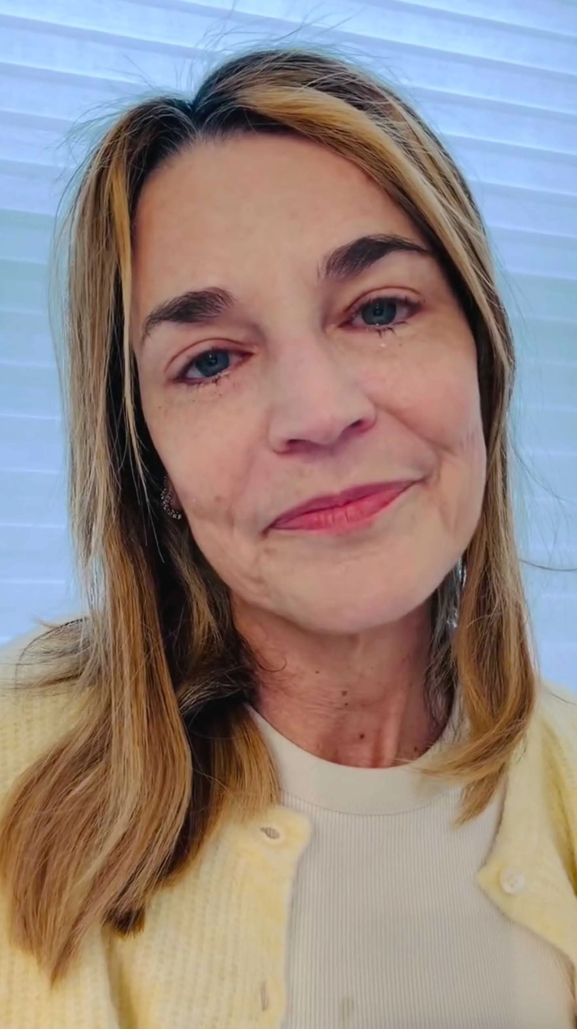 A woman with blonde hair, crying, looking at the viewer.