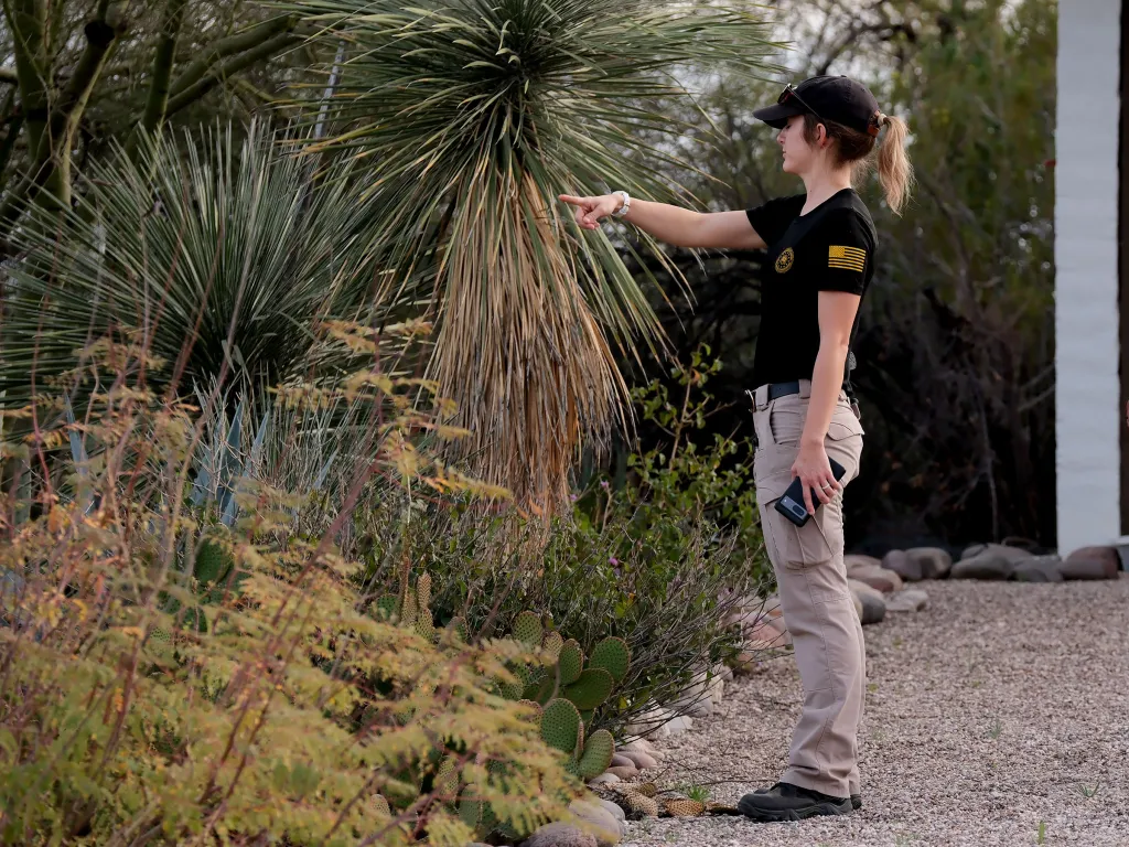 An FBI agent pointing to a yucca plant.