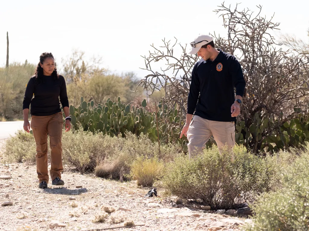 FBI officer points to a black item in the desert during a search for Nancy Guthrie.
