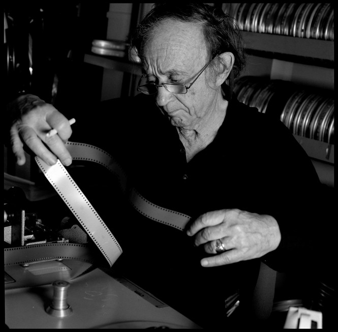 In a black and white photo a man looks at a film strip