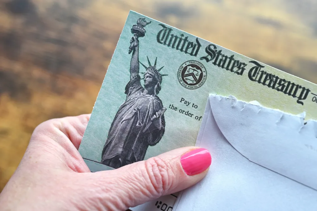 Female hand holding a check from the United States Treasury.