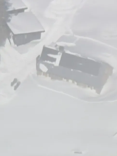 Aerial view of snow-covered buildings in Frog Lake after an avalanche.