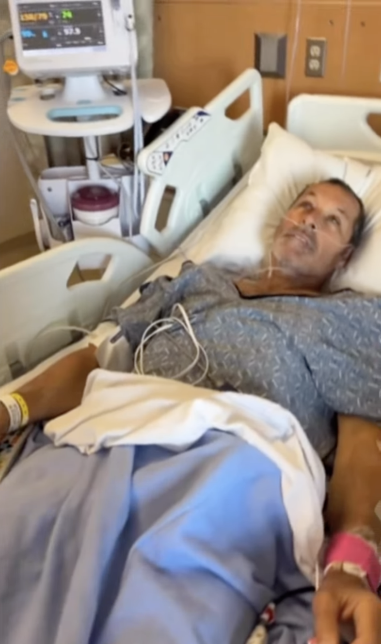 Ron Duguay lying in a hospital bed with a nasal cannula and an IV.