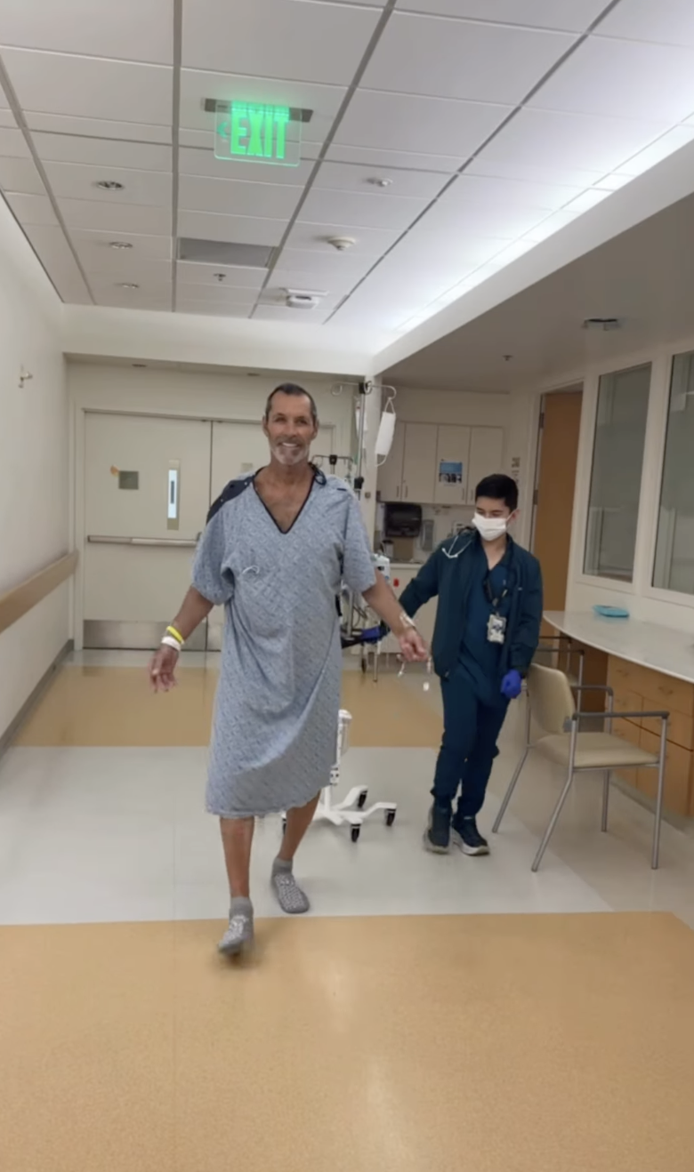 Former pro hockey player Ron Duguay walking with assistance from a medical professional in a hospital hallway.