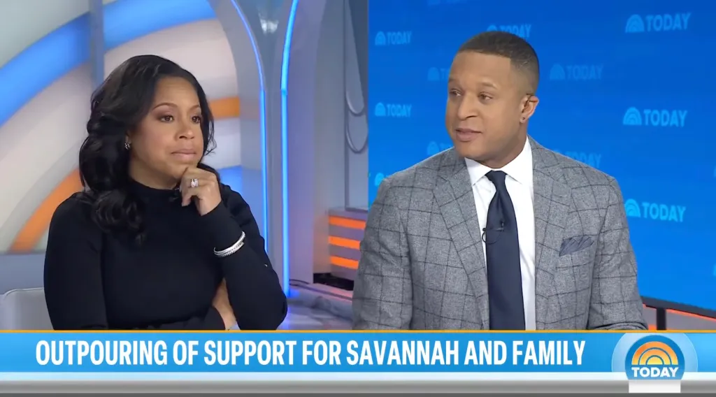 Sheinelle Jones, in black top, sits beside Craig Melvin, in a grey checked blazer, blue tie and white shirt.