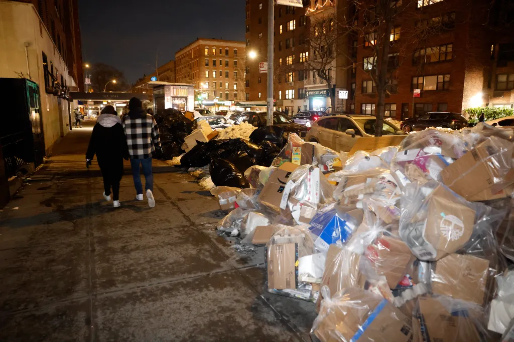 Garbage and recyclables piled up along East 79th Street in New York due to sanitation collection disruptions.