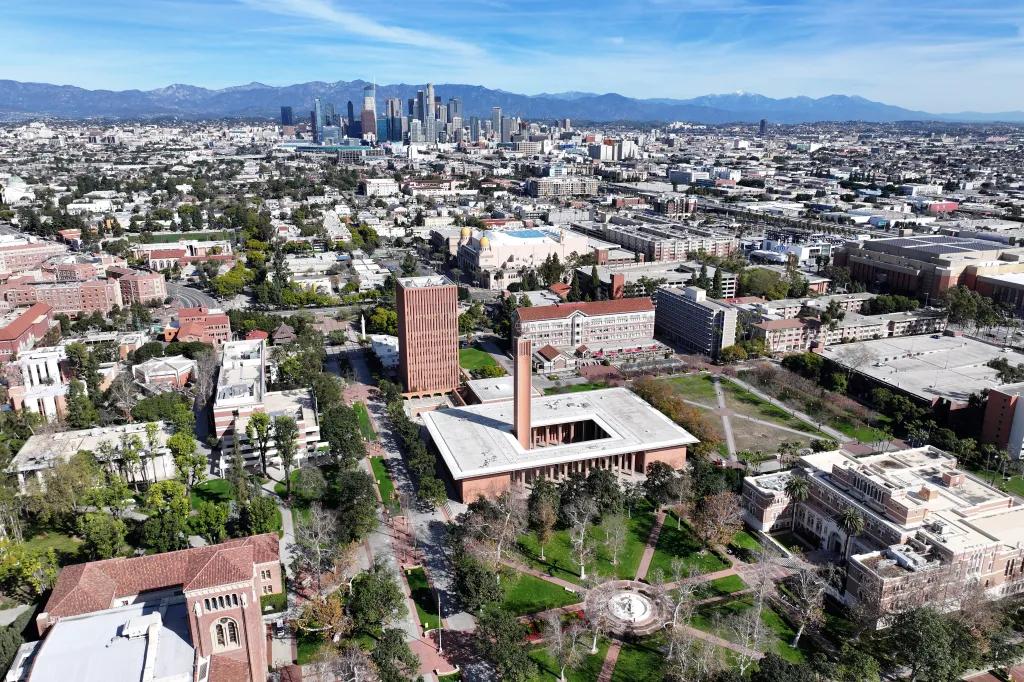 Aerial view of the University of Southern California campus with the downtown Los Angeles skyline and mountains in the background.