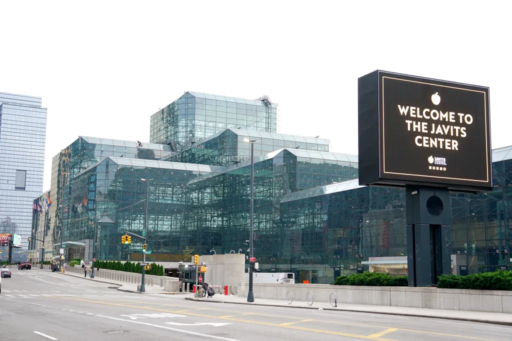 Exterior view of the Javits Center with a welcome sign and surrounding buildings.