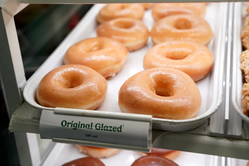 Trays of Krispy Kreme Original Glazed doughnuts in a store display.