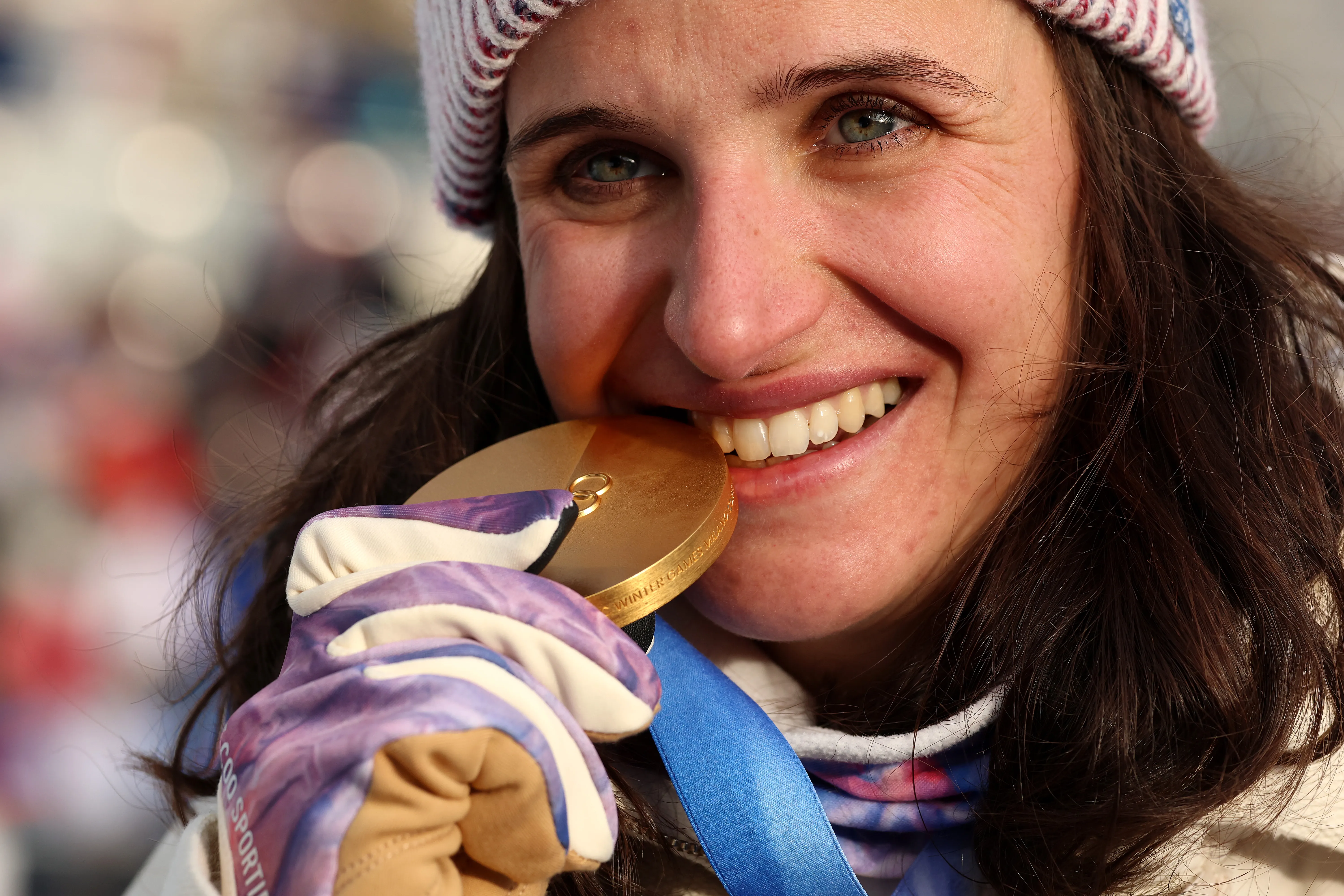 Julia Simon holds a gold medal up near her face.