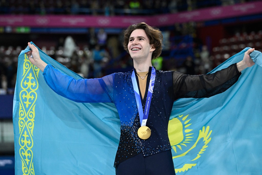 Mikhail Shaidorov, gold medalist in figure skating men's singles, holding the Kazakhstan flag.