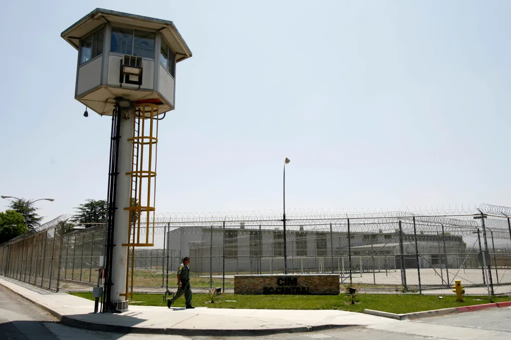 A guard walks past a watchtower outside the California Institution for Men in Chino.