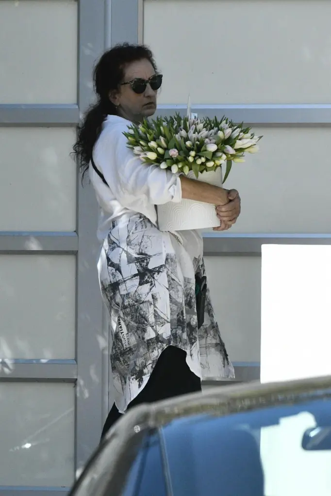 A guest or family member carrying a large arrangement of tulips to Catherine O'Hara's home.