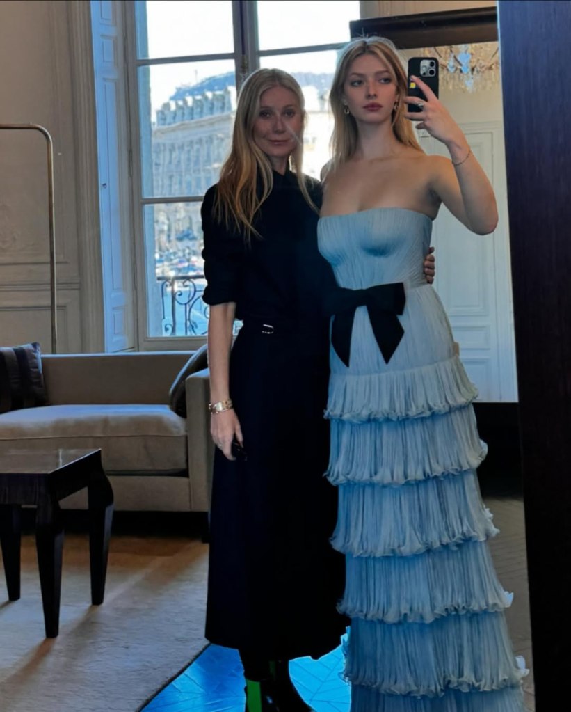 Gwyneth Paltrow in a black outfit and Apple Martin in a tiered, light blue gown with a black bow, posing in Paris.