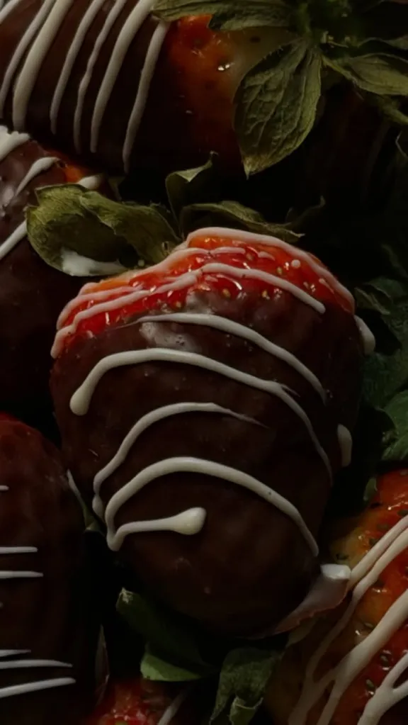 Close-up of chocolate-covered strawberries with white and red icing.